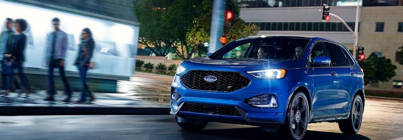 Blue 2019 Ford Edge driving city streets at night